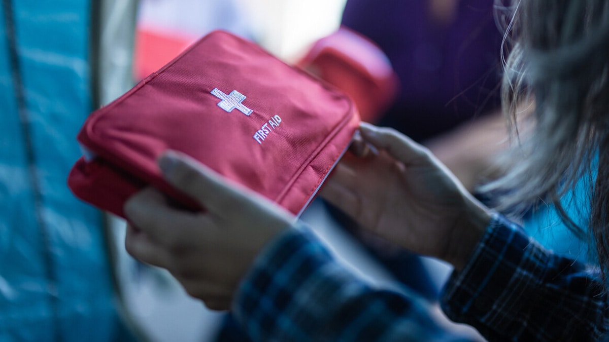 A woman in need holds a first aid kit.