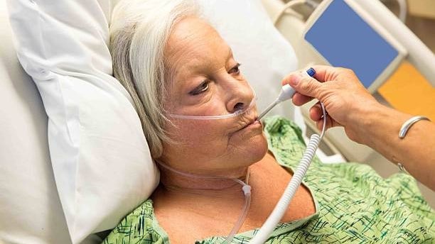 Person in a hospital bed getting their temperature taken