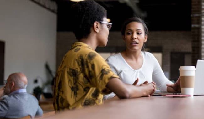 Two young women in coffee shop talking