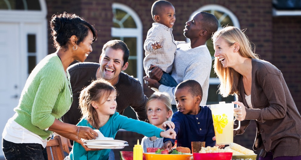 Two families sharing lunch together outdoors.