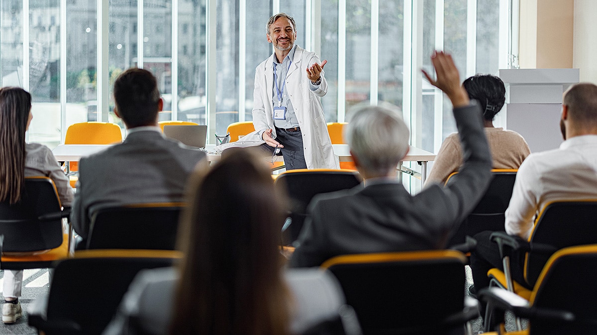 Doctor at head of conference room training room of business people.