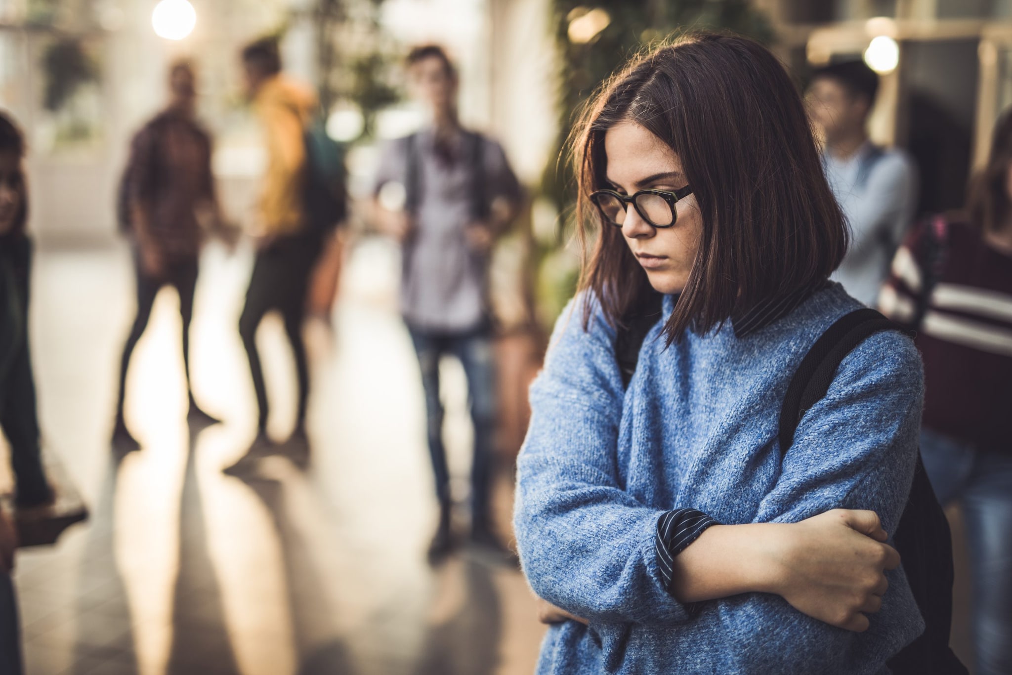 Sad female high school student standing alone in the hallway